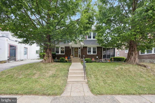 a front view of a house with a yard and large trees