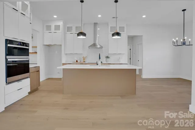 a large kitchen with kitchen island a large counter top stainless steel appliances and cabinets