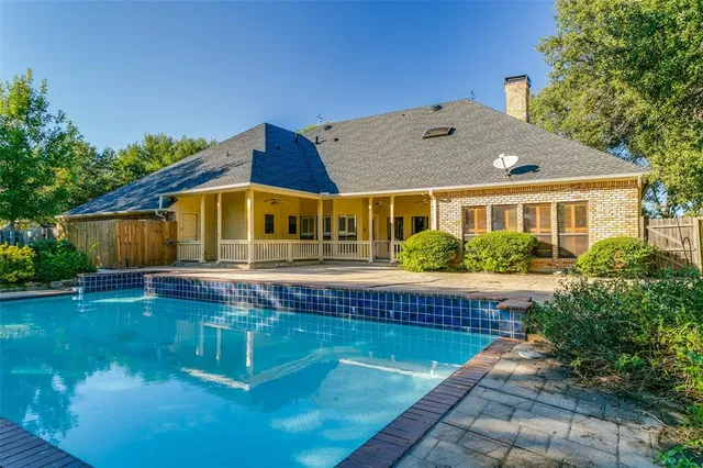 a view of swimming pool with lawn chairs and large trees