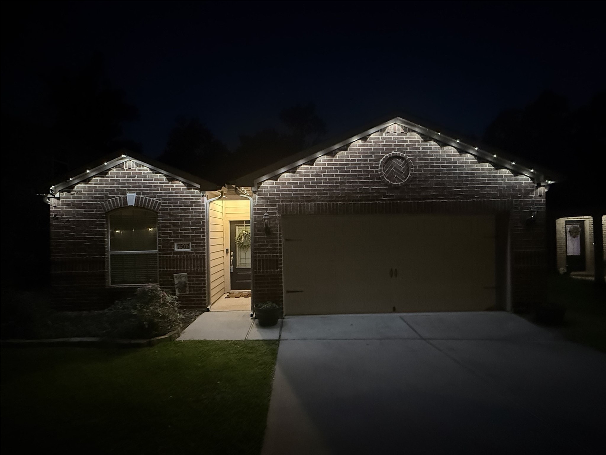 7562 Fettle Lane Conroe, TX 77304 - Photo 5 of 30 Evening exterior view showcasing permanent customizable exterior lighting conveniently controlled through a mobile app for year-round ambiance and holiday displays.