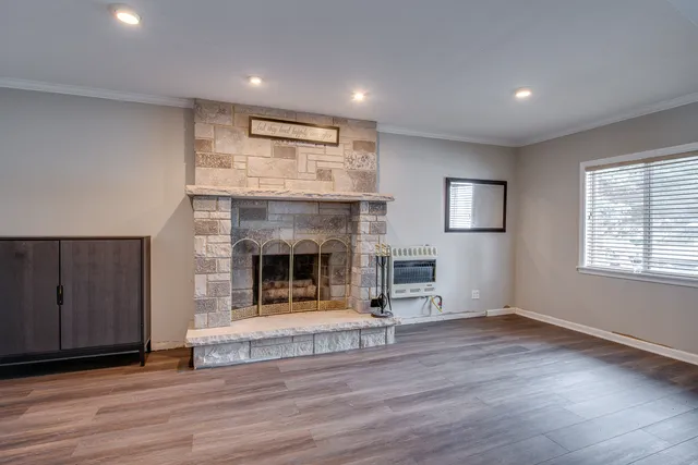 an empty room with wooden floor fireplace and windows