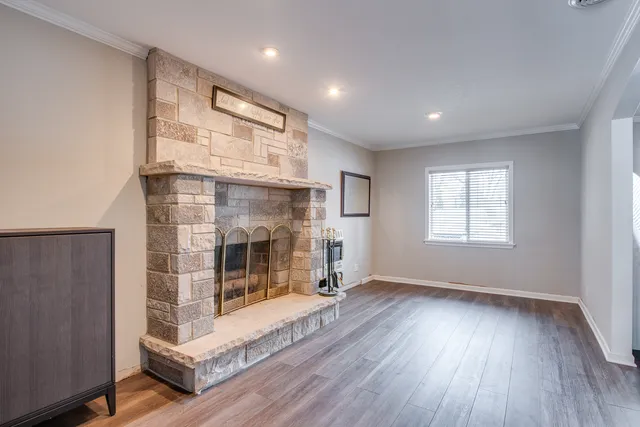 a view of an empty room with wooden floor and a fireplace