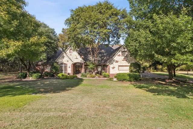 a view of a house with a yard and large trees