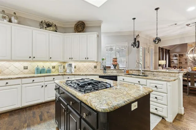 a kitchen with stainless steel appliances granite countertop a stove a sink dishwasher and white cabinets with wooden floor