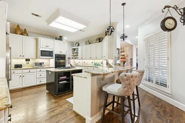 a kitchen with a refrigerator a stove a sink dishwasher a dining table and chairs with wooden floor