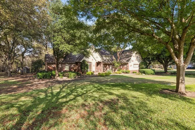 a view of a house with a big yard and large trees