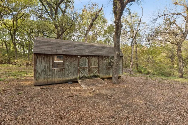 a view of wooden house with large trees