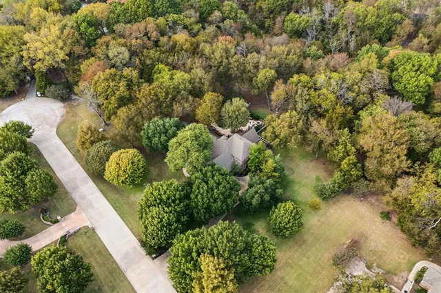 an aerial view of residential house with outdoor space and trees all around
