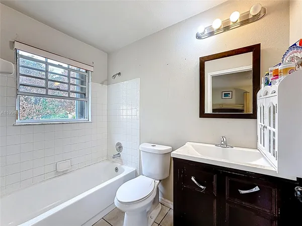 a bathroom with a toilet a sink a tub and a mirror