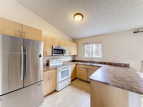 a kitchen with granite countertop a refrigerator stove and sink