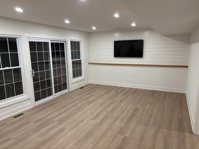 a view of an empty room with a flat tv screen and windows
