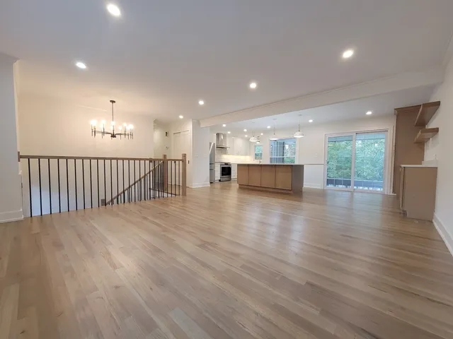 a view of a big room with wooden floor and windows
