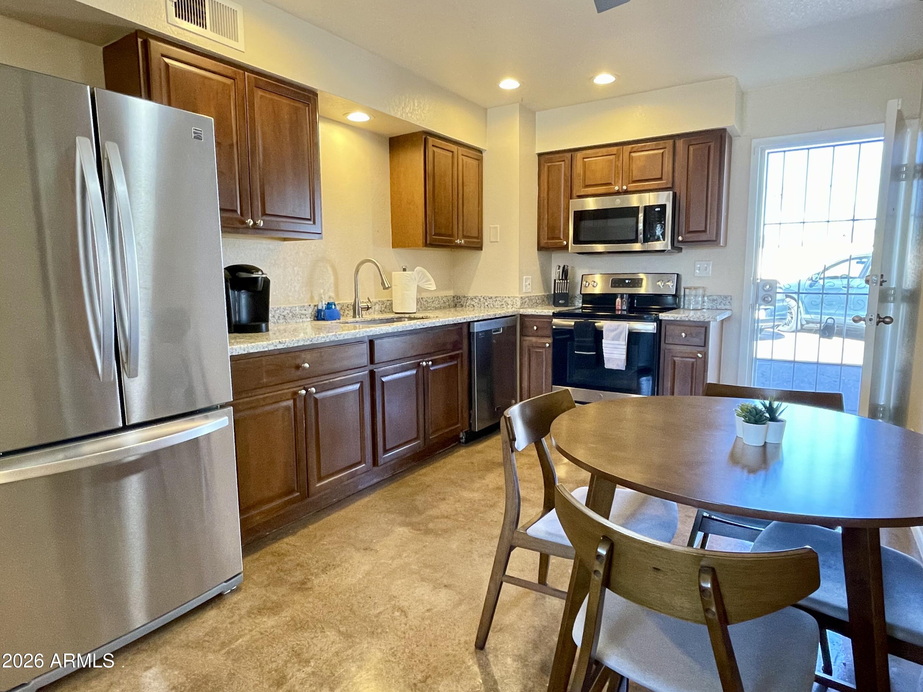 6819 North 12th Street, Unit 9 Phoenix, AZ 85014 - Photo 4 of 21 a kitchen with stainless steel appliances granite countertop a stove a sink a microwave a refrigerator a dining table and chairs