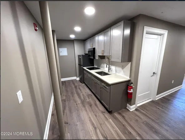 a kitchen with sink a refrigerator and wooden floor