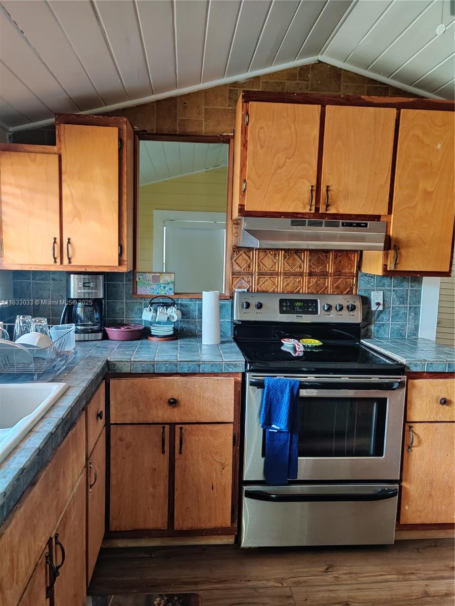 16475 Southwest 248th Street, Unit 16475 Homestead, FL 33031 - Photo 3 of 8 a kitchen with stainless steel appliances wooden cabinets and a stove