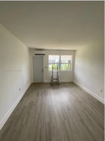 a view of an empty room with wooden floor and closet