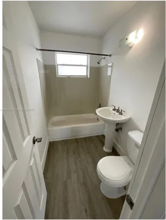 a view of an empty room with kitchen view and a window