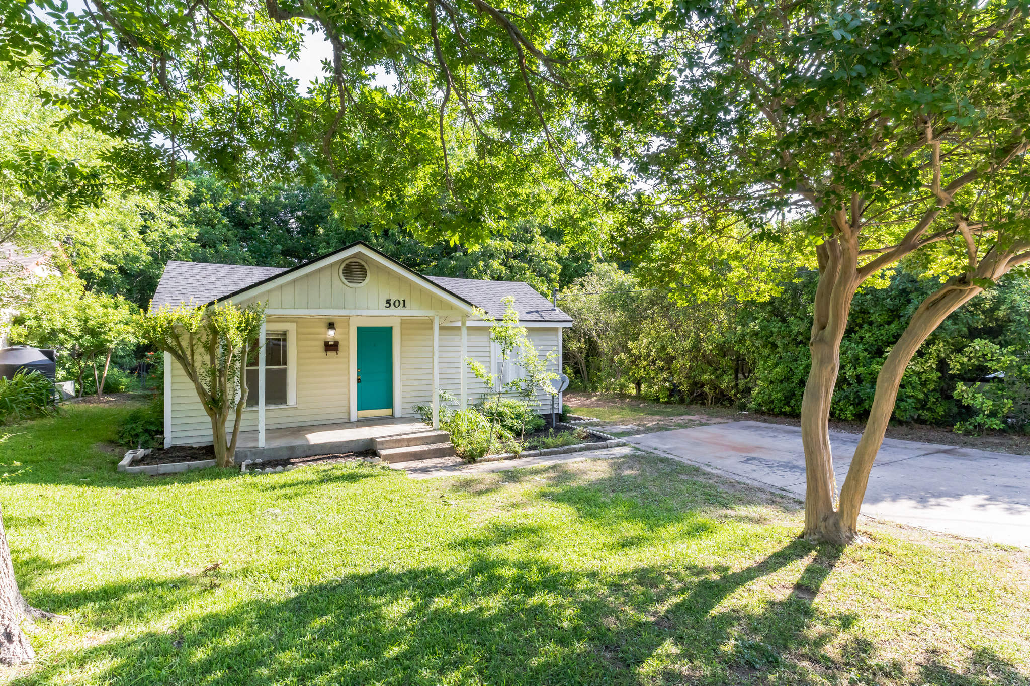 501 East 4th Street Georgetown, TX 78626 - Photo 2 of 25 Bungalow-style house with a porch, roof with shingles, a front yard, and view of wooded area
