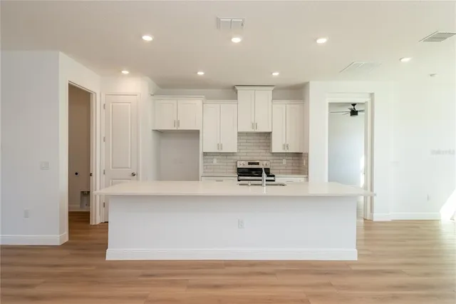 a large kitchen with stainless steel appliances granite countertop a stove a sink and white cabinets