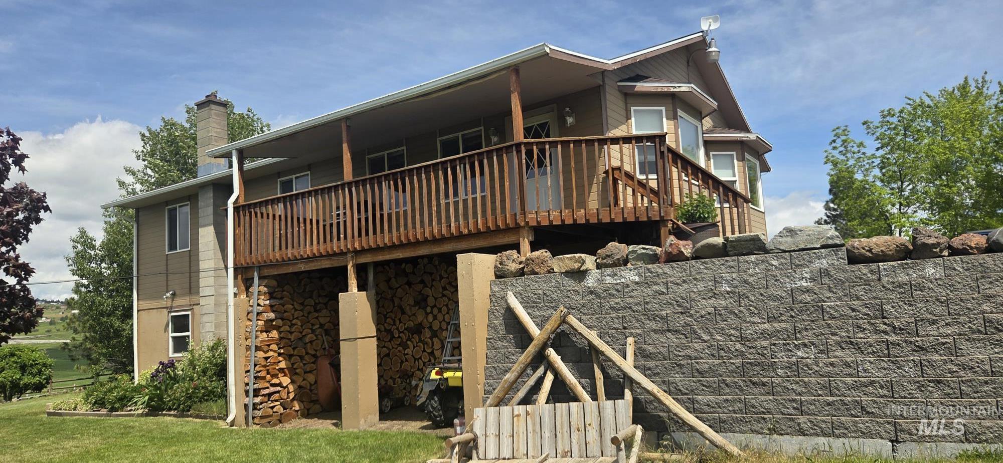 394 Substation Road Cottonwood, ID 83522 - Photo 7 of 37 Expansive wood deck with a covered area, a stone retaining wall, and a chimney feature