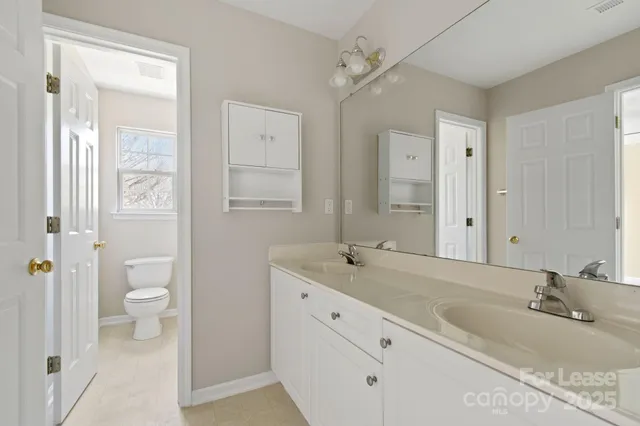 a bathroom with a granite countertop sink a toilet and a large mirror