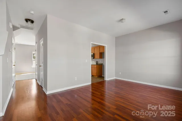 a view of an empty room with wooden floor and a cabinet