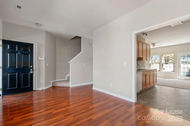 a view of a livingroom with wooden floor and a kitchen