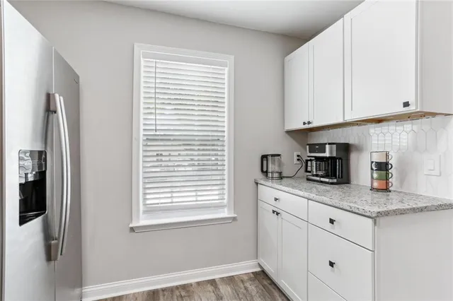 a kitchen with granite countertop stainless steel appliances white cabinets and a window