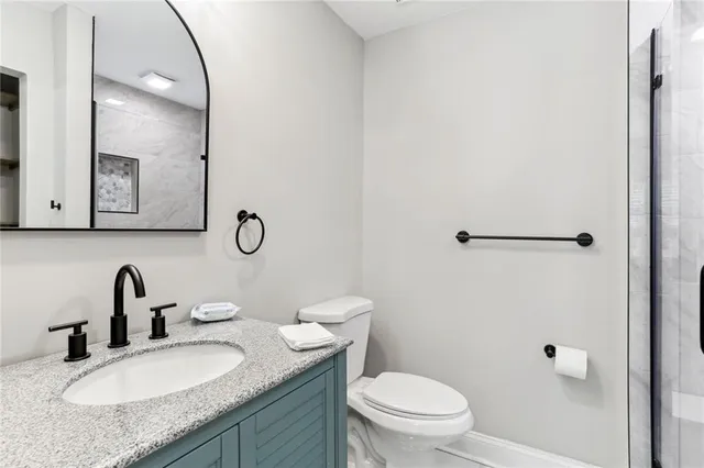 a bathroom with a granite countertop sink a toilet and a mirror