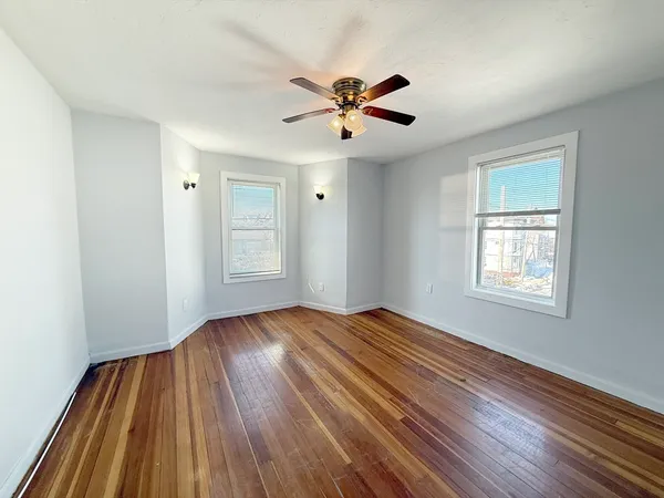 a view of empty room with wooden floor and fan
