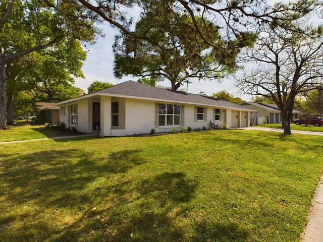a front view of a house with a garden and trees