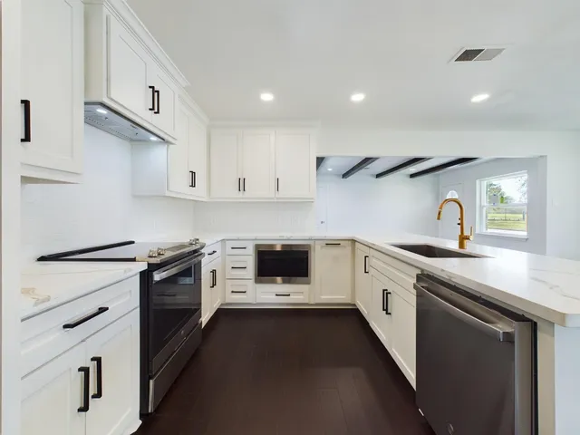 a kitchen with granite countertop white cabinets and white appliances