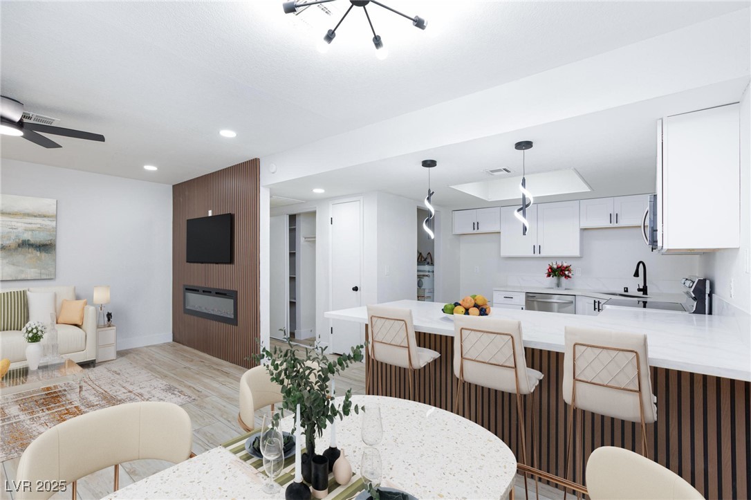 5905 Smoke Ranch Road, Unit A Las Vegas, NV 89108 - Photo 11 of 31 Dining area featuring light wood-style flooring, recessed lighting, and a fireplace