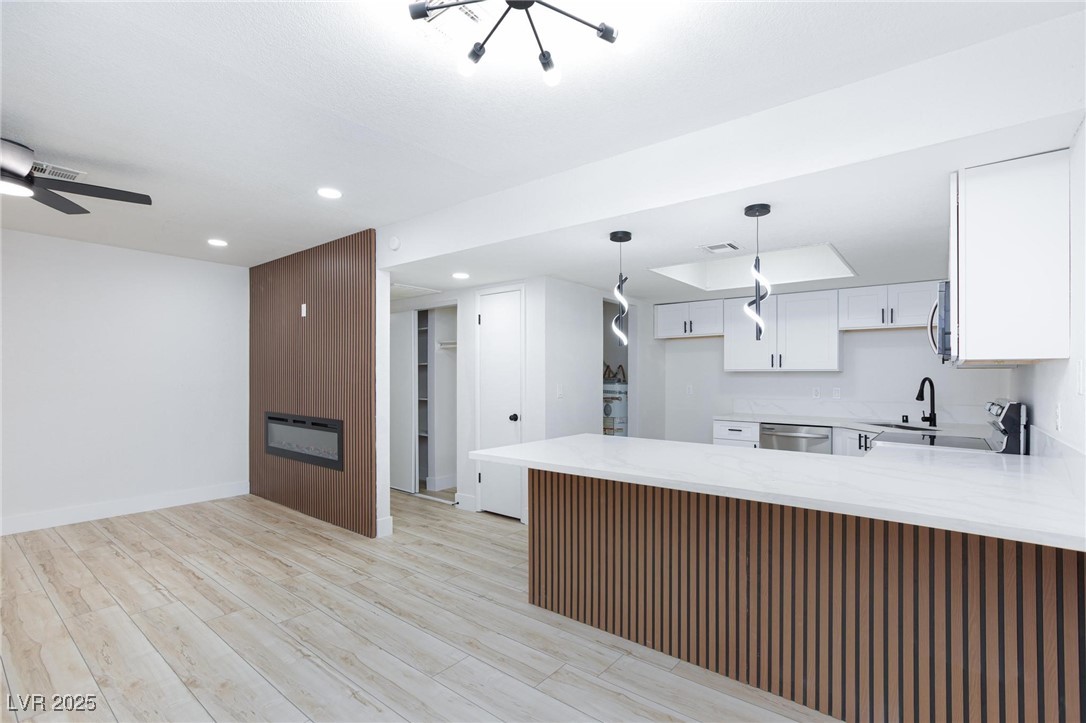 5905 Smoke Ranch Road, Unit A Las Vegas, NV 89108 - Photo 12 of 31 Kitchen with light stone counters, white cabinetry, light wood-type flooring, a peninsula, and recessed lighting