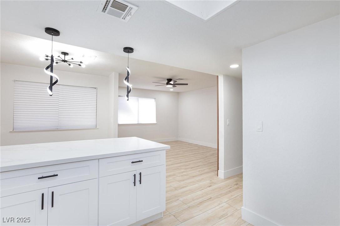 5905 Smoke Ranch Road, Unit A Las Vegas, NV 89108 - Photo 31 of 31 Kitchen with light stone counters, light wood-style flooring, white cabinets, pendant lighting, and open floor plan