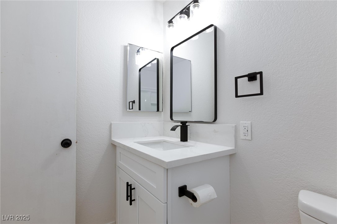 5905 Smoke Ranch Road, Unit A Las Vegas, NV 89108 - Photo 19 of 31 Half bath featuring a textured wall and vanity