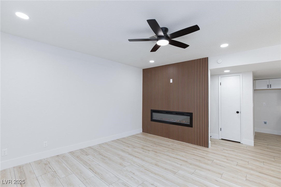 5905 Smoke Ranch Road, Unit A Las Vegas, NV 89108 - Photo 2 of 31 Unfurnished living room with recessed lighting, a ceiling fan, light wood-type flooring, and a glass covered fireplace