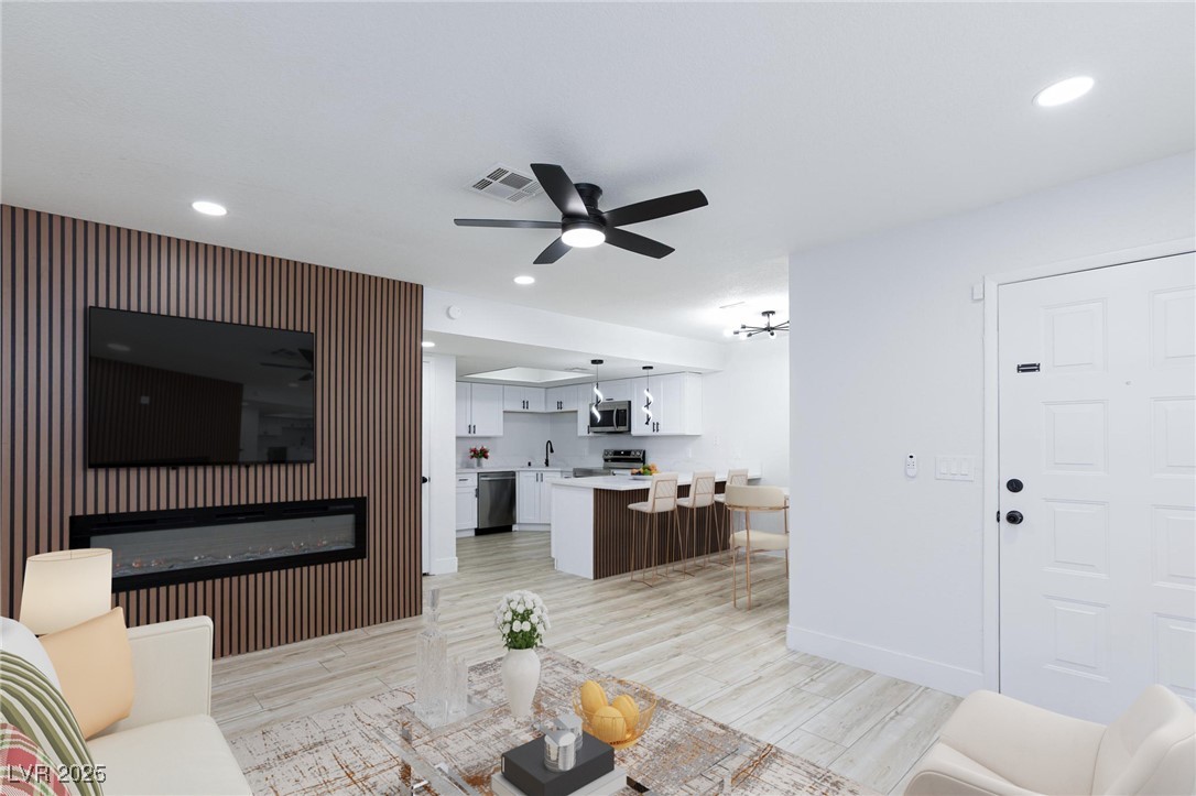 5905 Smoke Ranch Road, Unit A Las Vegas, NV 89108 - Photo 3 of 31 Living room featuring recessed lighting, light wood-style flooring, a ceiling fan, and a glass covered fireplace