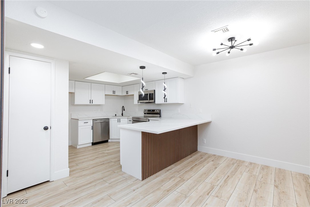 5905 Smoke Ranch Road, Unit A Las Vegas, NV 89108 - Photo 9 of 31 Kitchen with a peninsula, pendant lighting, light wood-type flooring, appliances with stainless steel finishes, and recessed lighting