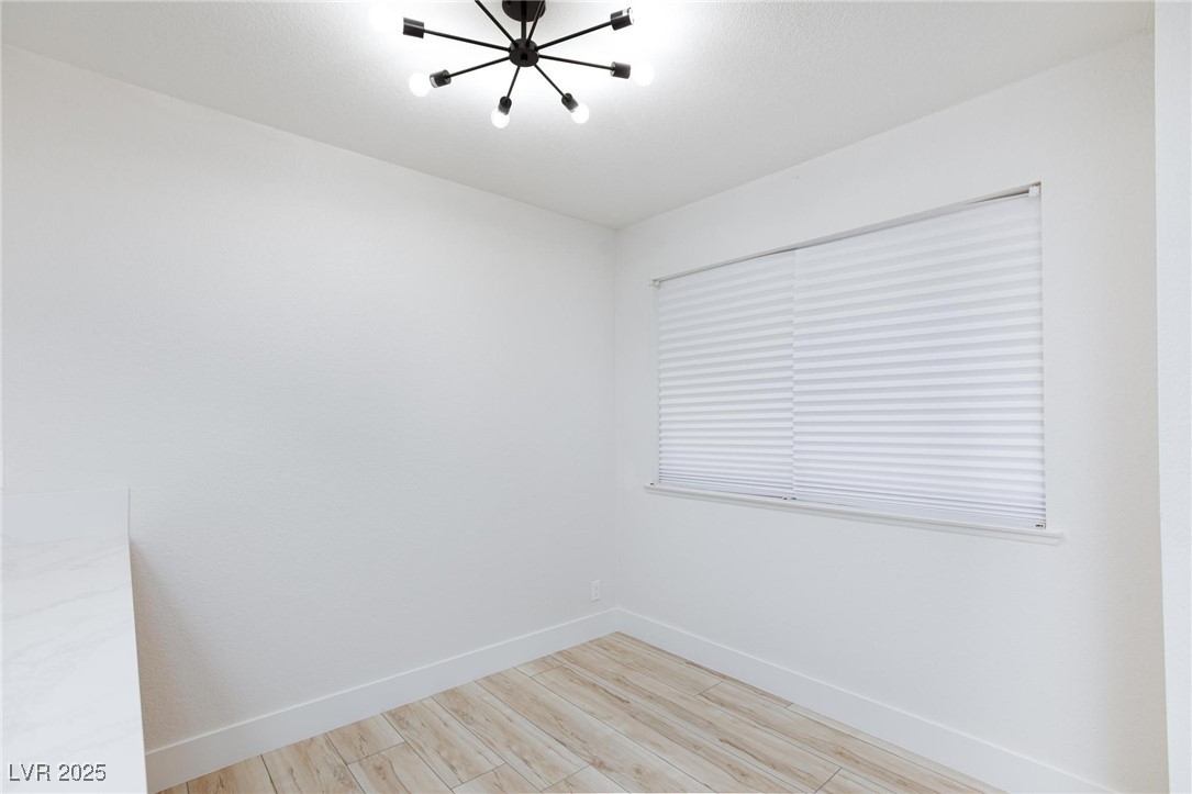 5905 Smoke Ranch Road, Unit A Las Vegas, NV 89108 - Photo 10 of 31 Empty room with light wood-type flooring and a chandelier