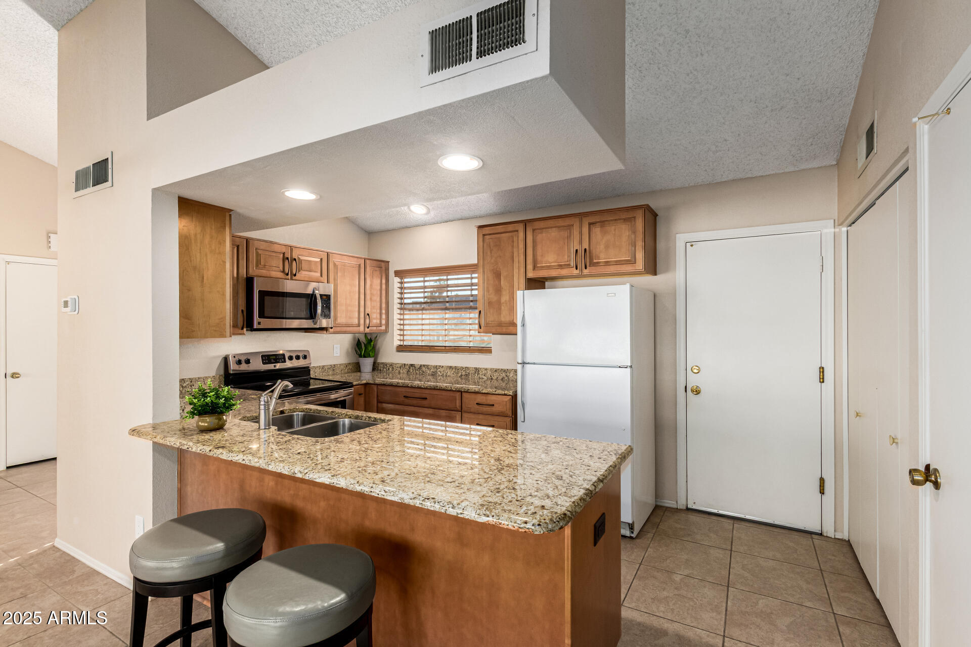 1312 East Stephens Drive Tempe, AZ 85283 - Photo 8 of 26 a kitchen with stainless steel appliances granite countertop a refrigerator and a stove top oven