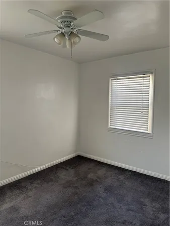 an empty room with a window and a ceiling fan