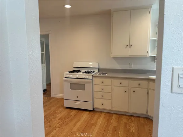 a kitchen with stainless steel appliances granite countertop a stove a sink and white cabinets with wooden floor