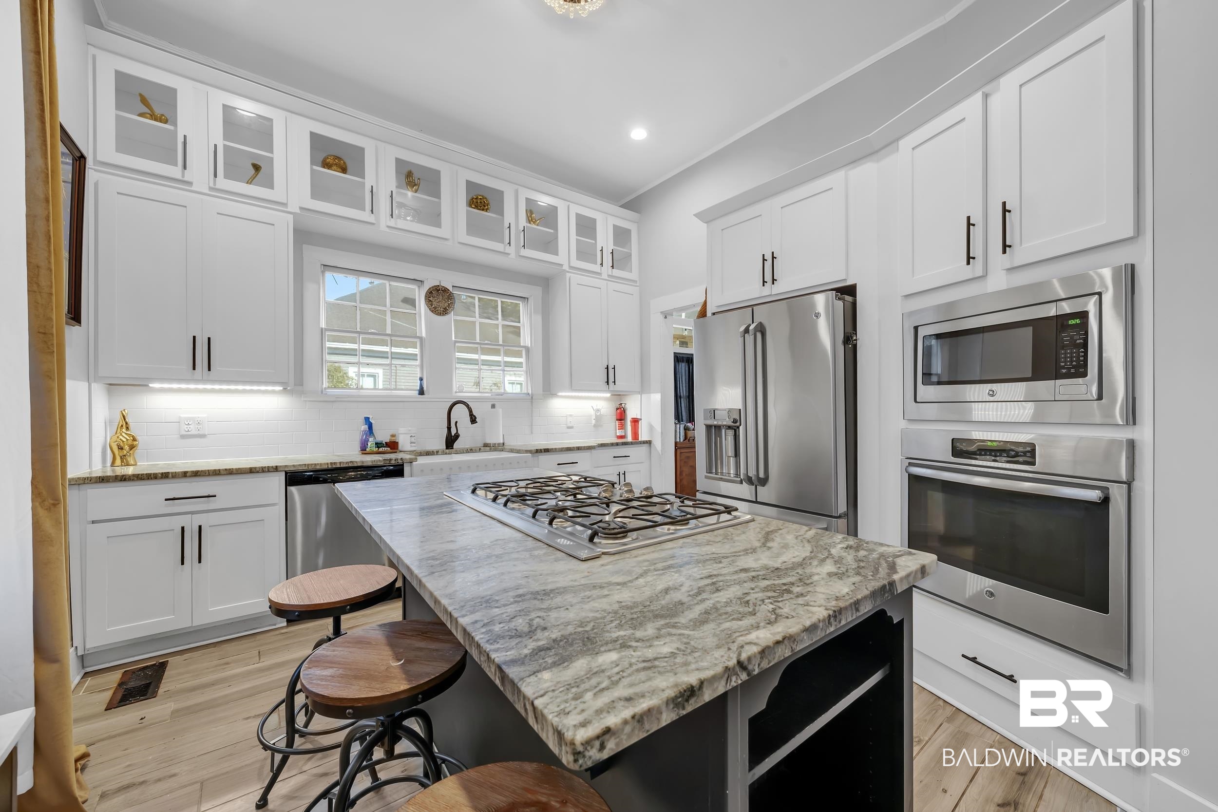 1322 Dauphin Street Mobile, AL 36604 - Photo 11 of 21 Kitchen with stainless steel appliances, a breakfast bar, light stone countertops, a kitchen island, and glass insert cabinets