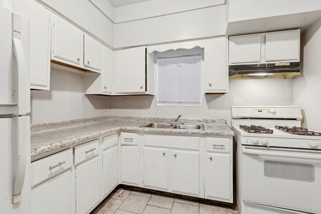 1912 South Harding Avenue Chicago, IL 60623 - Photo 4 of 16 a kitchen with granite countertop white cabinets and white appliances