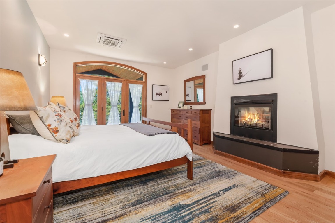 2911 Inverness Way Steamboat Springs, CO 80487 - Photo 23 of 43 a bedroom with a bed and a fireplace with wooden floor