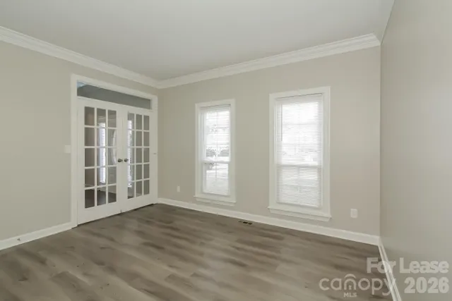 an empty room with wooden floor and windows
