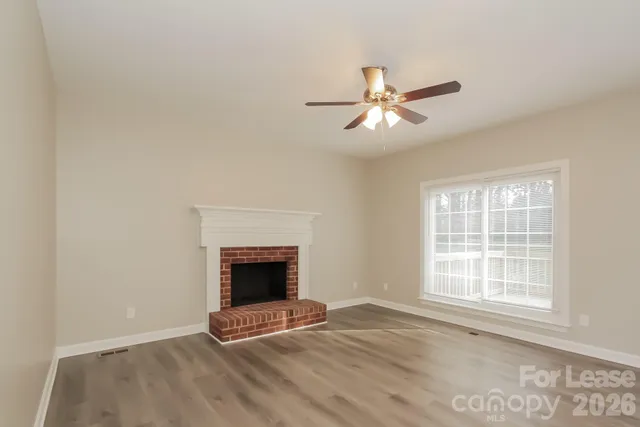 a view of an empty room with window and chandelier fan