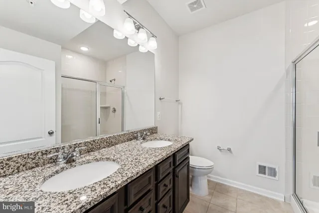 a bathroom with a granite countertop sink a toilet and shower
