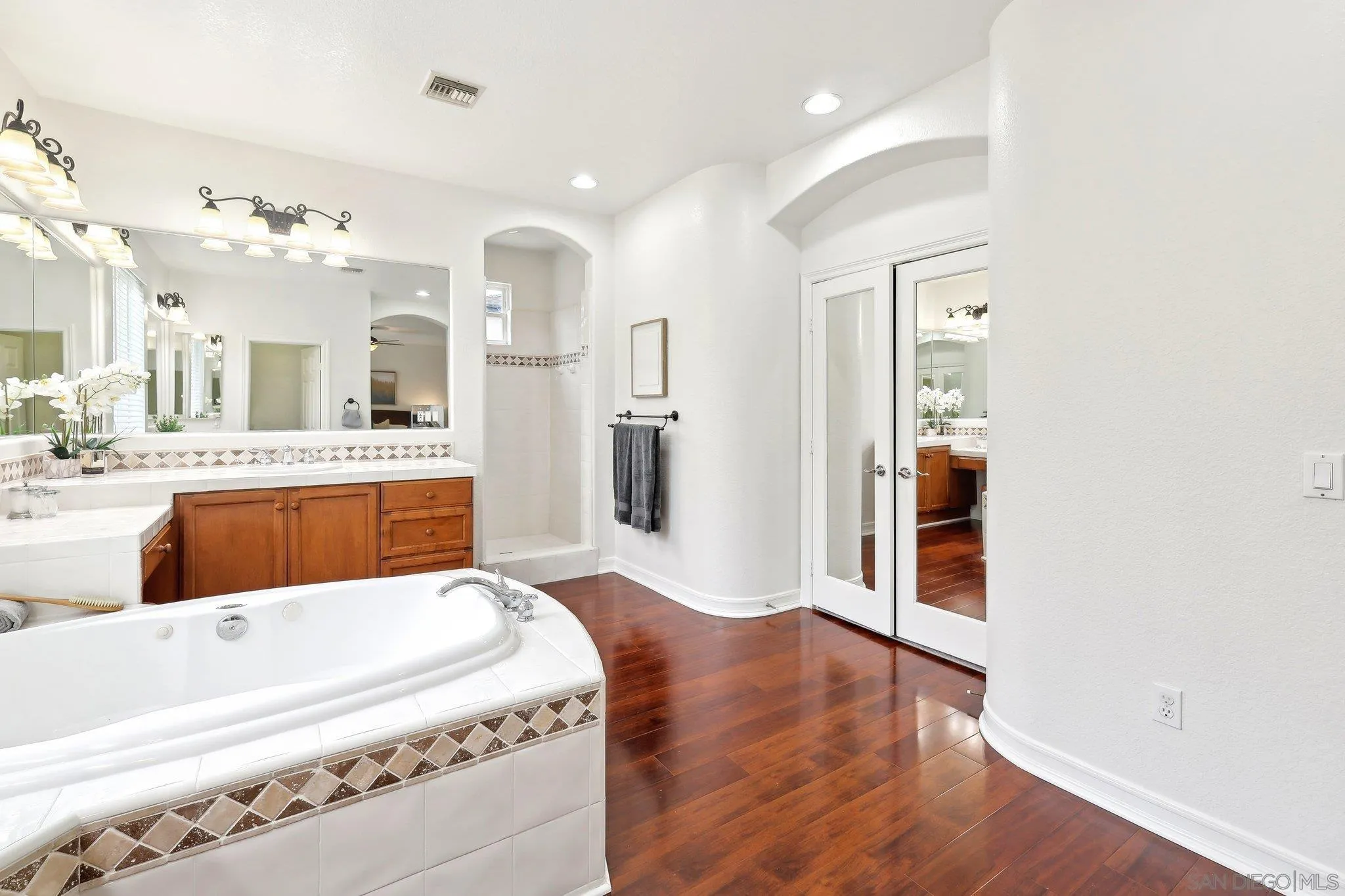 11781 Treadwell Drive Poway, CA 92064 - Photo 39 of 63 a large white kitchen with a refrigerator a sink dishwasher and white cabinets with wooden floor